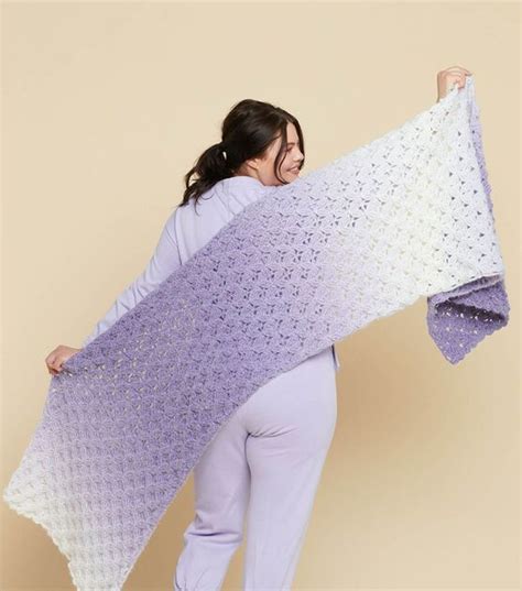 A Woman Is Holding Up A Crocheted Blanket