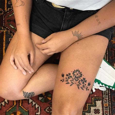 A Woman Sitting On The Floor With Her Legs Crossed And Tattoos On Her Leg