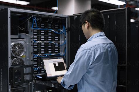 Server Room Technician Using Computer In Server Room By Stocksy