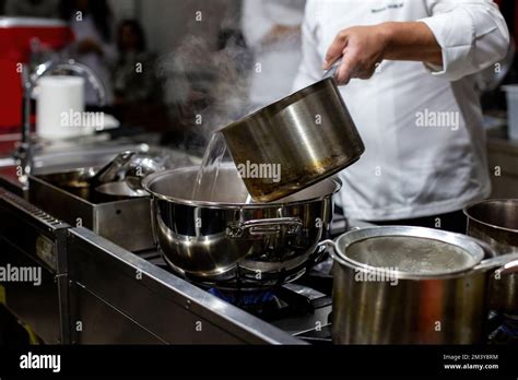 The Cook Pours Hot Water From Pot To Pot Stock Photo Alamy
