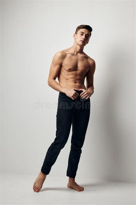 A Man In Jeans Stands On The Floor In A Room With A Naked Torso In Full Growth Stock Photo