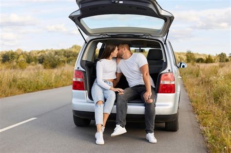 Porträt eines liebespaares das in seinem auto im kofferraum in der