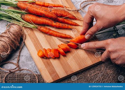 Cortar Zanahorias En La Cocina En Una Tabla De Cortar Imagen De Archivo