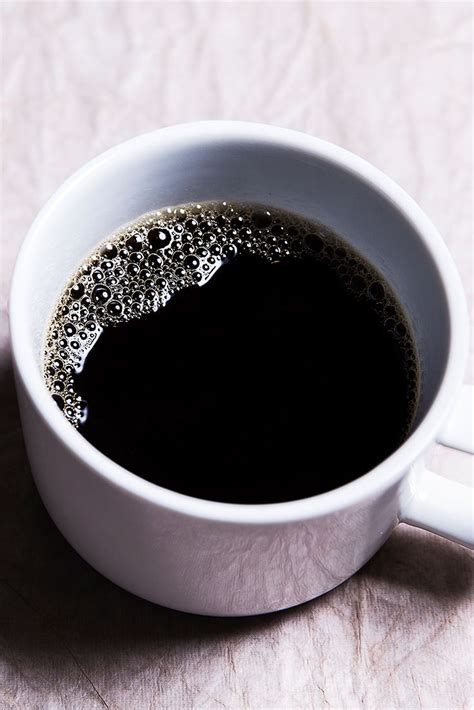 A White Cup Filled With Liquid On Top Of A Table