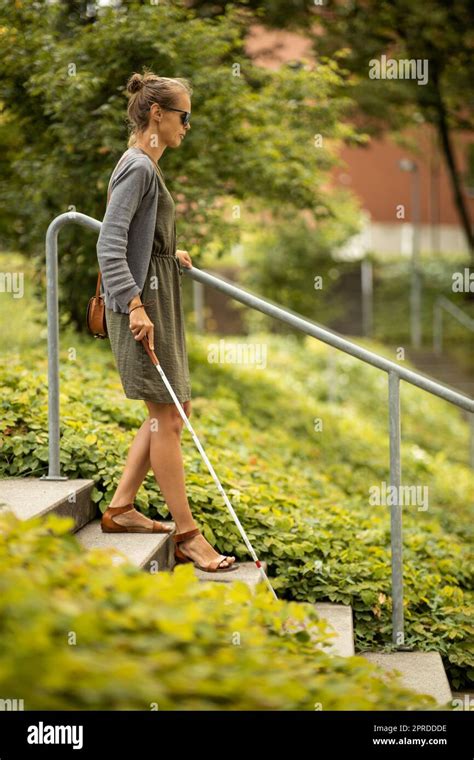 Blind Woman Walking On City Streets Using Her White Cane To Navigate