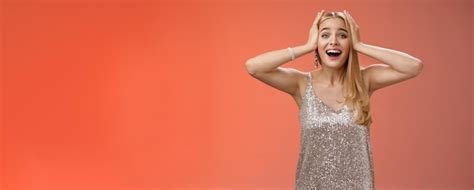 Étonnée excitée nerveuse jeune belle blonde vêtue d une robe argentée et élégante elle n