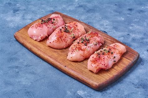 Free Photo Raw Chicken Fillet On A Wooden Board On Blue