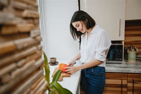 Junger Und H Bscher Brunette Der Das Fenster In Der K Che Mit Orange Bereitsteht Kostenlose Foto