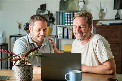 Una pareja gay de chicos maduros sonriendo en la terraza de su casa abrazándose Foto Premium