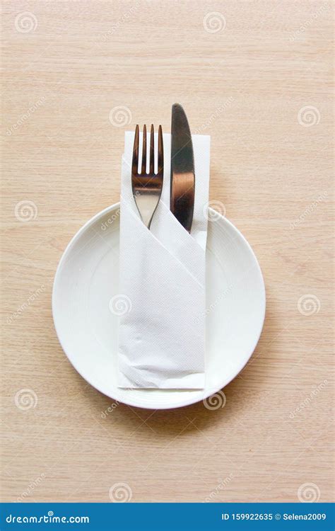 Knife And Fork Wrapped In A Napkin Lying On A White Plate The View