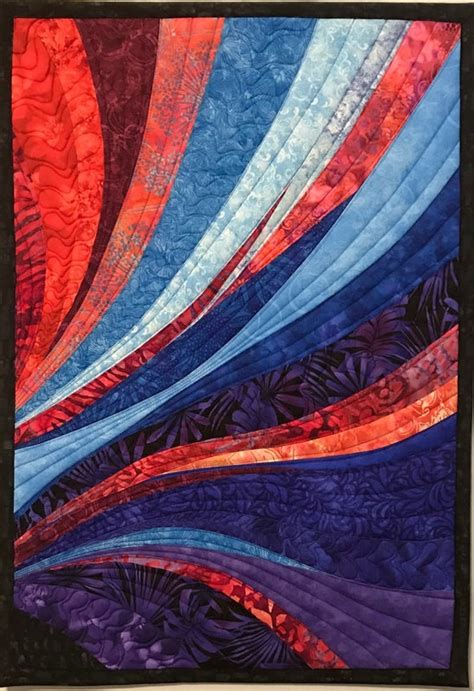 A Quilted Wall Hanging On The Side Of A Building With An Abstract Design In Red Blue And Purple