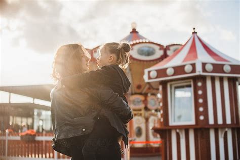 Mother Holding Her Daughter On Her Arms In The Amusement Park Del