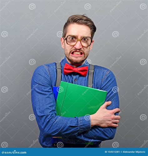 Portrait Of A Nerd Holding Book With Retro Glasses Against Gray