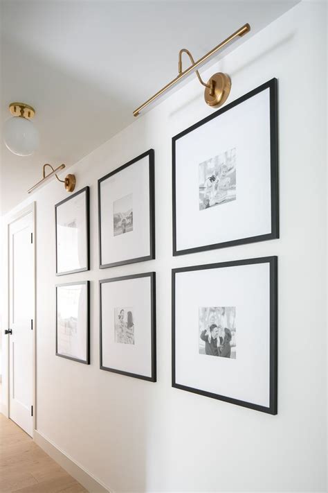 Large Square Grid Gallery Wall In A Hallway With Brass Picture Lights