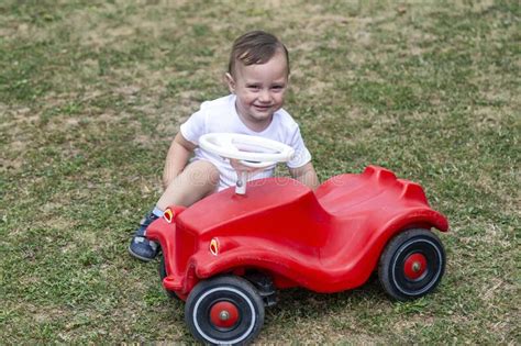 Garotinho Brincando Com Carro De Brinquedo Vermelho Imagem De Stock