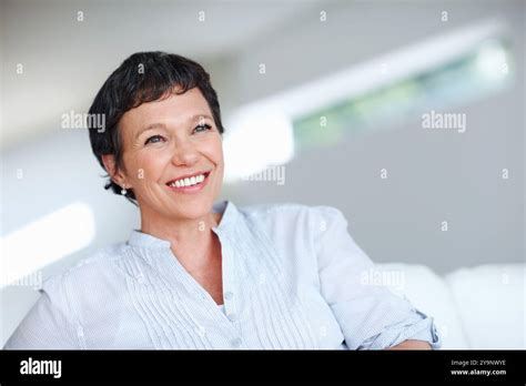 Mature Woman Happy And Thinking On Sofa In Home With Nostalgia Memory