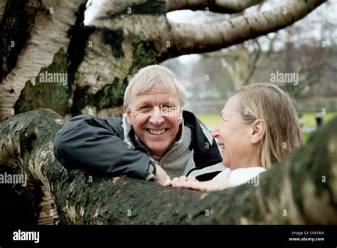 Senior Couple Leaning Against Tree Smiling Stock Photo Alamy