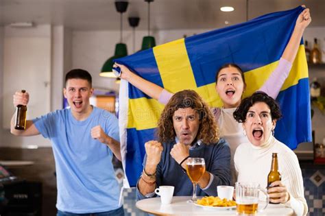 Company Of Excited Young Adult Sports Fans Waving Flag Of Sweden And