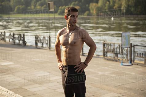 Fit Shirtless Man Standing With Hands On Hips On City Sidewalk Looking