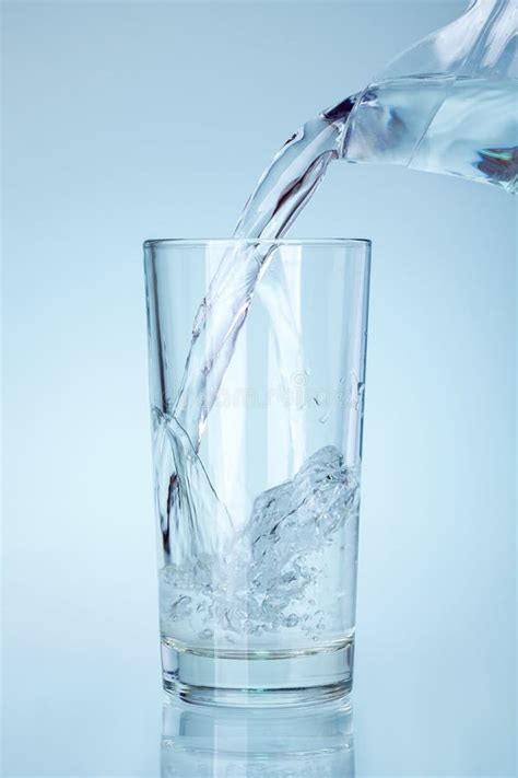 The Clear Glass Is Filled With Water From The Spout Of The Glass Jug