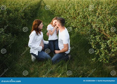 Beautiful Pregnant Brunette Mom And Dad And Dauther In White Clothes Look At Each Other In