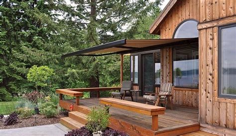 a wooden deck with chairs and an awning over it next to a house in the ...