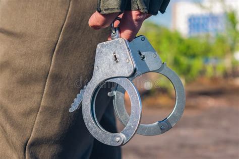 Handcuffs In The Hands Of A Policeman Close Up Police Equipment Part