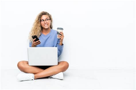 Menina de cabelo encaracolado um laptop sentada no chão segurando