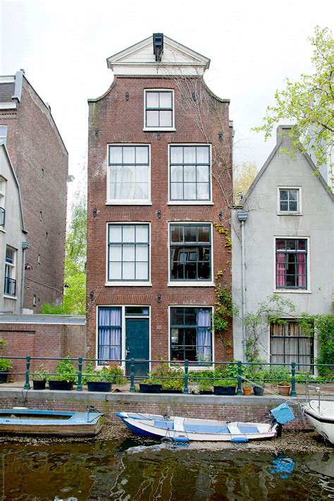 The Facade Of An Old Canal House In Amsterdam Surrounded By Flowers