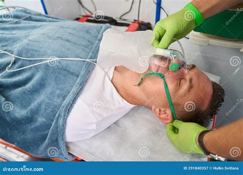 Paramedic Puts Oxygen Mask On Woman Liyng On Stretcher In The Ambulance