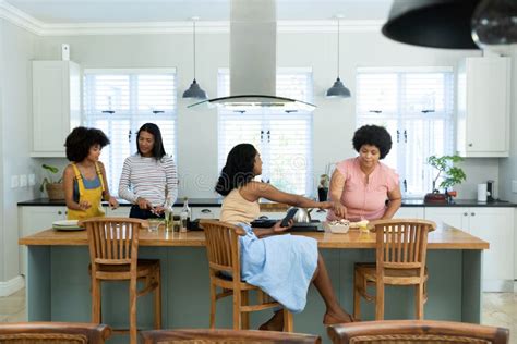 Biracial Female Friends Preparing Pizza On Kitchen Island While