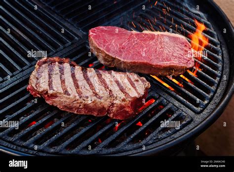 Raw Dry Aged Wagyu Roast Beef Steak Grilled As Close Up On A Charcoal Grill With Fire And Smoke