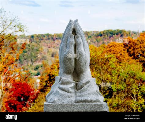 Stone Praying Hands In Front Of A Lush Foliage Backdrop In West