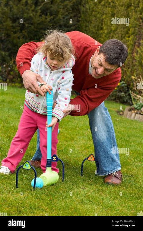 Adult Male Teaching A Young Girl How To Play Croquet In An English