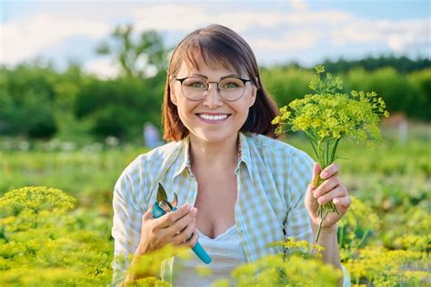 Sonriente Mujer De Mediana Edad Con Podadora Recogiendo Ramas De Eneldo