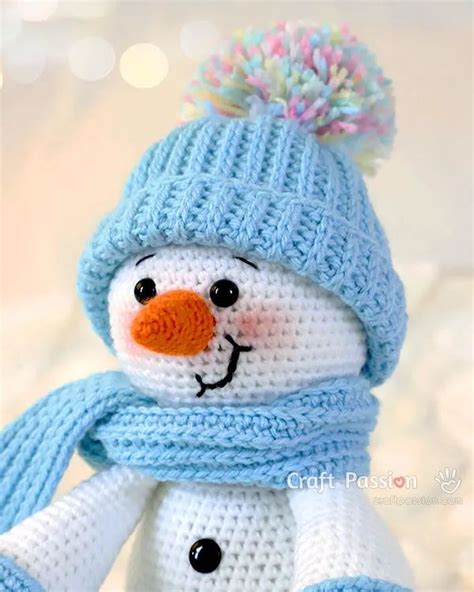 A Crocheted Snowman Wearing A Blue Hat And Scarf