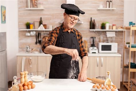 Lächelnder Senior Bäcker in der heimischen Küche mit Bio Zutaten für