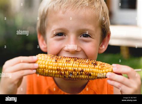Small Boy Eating Grilled Corn On The Cob Stock Photo Alamy