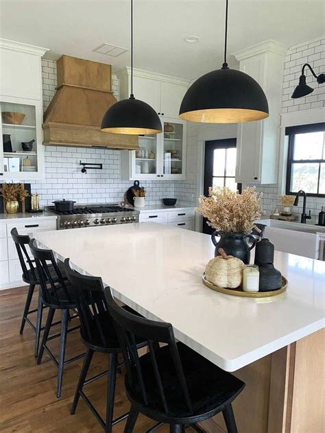 A Large Kitchen With White Counter Tops And Black Chairs In Front Of An Island Top