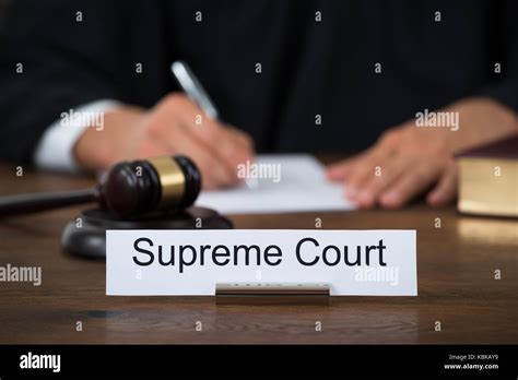 Supreme Court Nameplate With Judge Writing On Paper At Table In