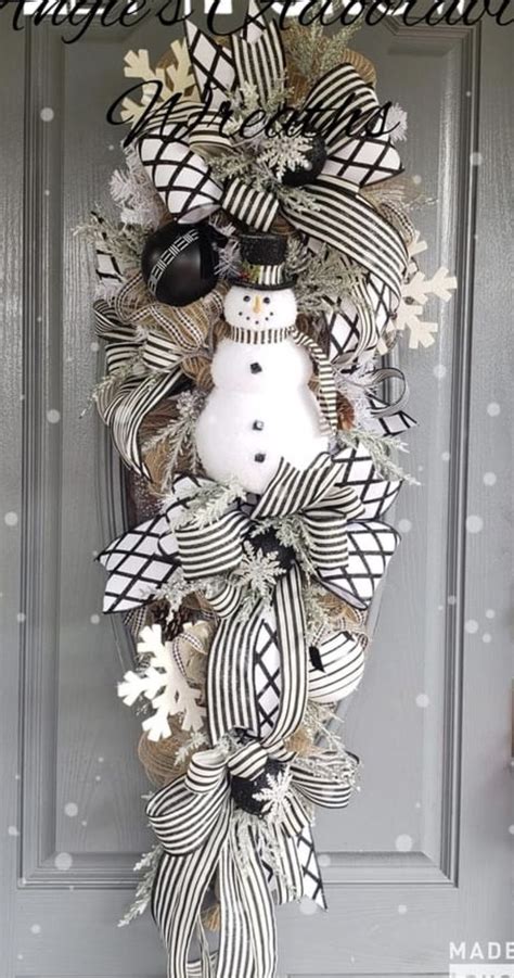 A Snowman Wreath With Black And White Ribbons Hanging On The Front Door