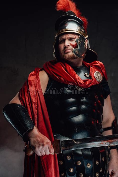 Warlike Roman With Dark Armour And Sword In Dark Background Stock Photo