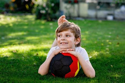 Happy Active Kid Boy Playing Soccer With Ball In German Flag Colors