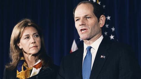 A Man And Woman Are Standing In Front Of An American Flag At A Press Conference