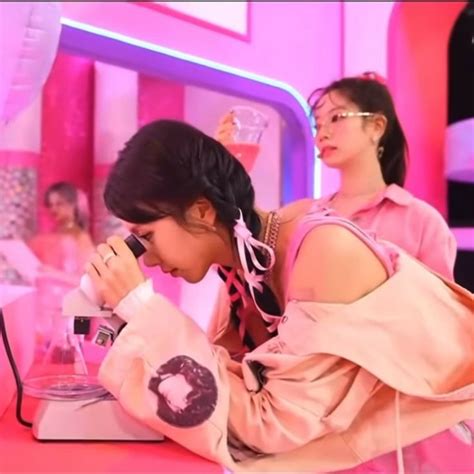 Two Women In Pink Outfits Are Looking At Items On A Table And One Woman