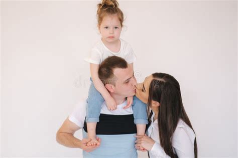 Adorable Little Girl Sits On Dad`s Neck Mom Kiss Dad Stock Photo