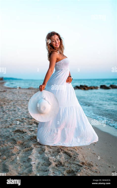 Beautiful Young Smiling Woman In White Dress Walking On The Beach And