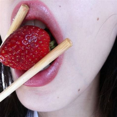 A Woman With Strawberries Sticking Out Of Her Tongue And Holding Two