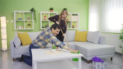 Happy Dancing Man And Woman Using Duster And Mop While Cleaning House Happy Dancing Couple