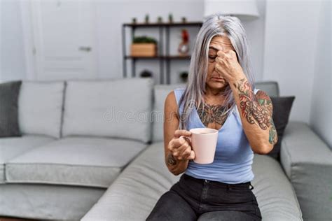 Middle Age Grey Haired Woman Drinking Coffee Sitting On The Sofa At